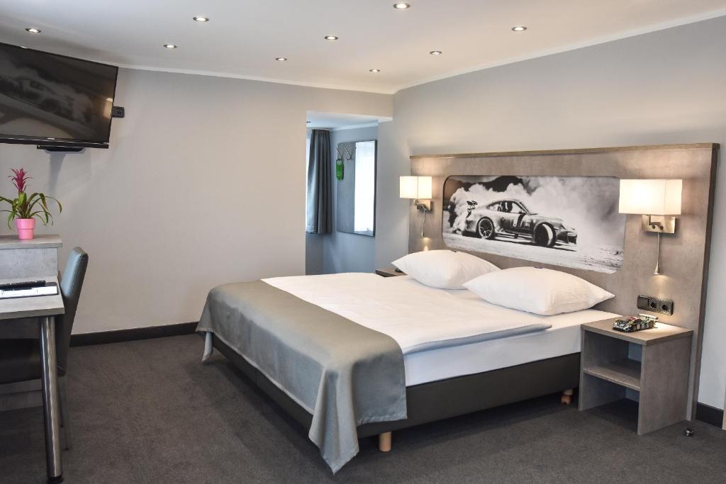 1 dormitorio con 1 cama grande y una foto de coche en la pared en GT3 Hotel en Honerath