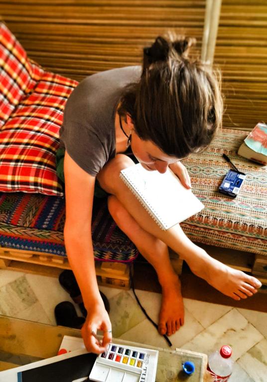 a woman is laying on the floor with a book and a laptop at JHouse near Bhikaji in New Delhi