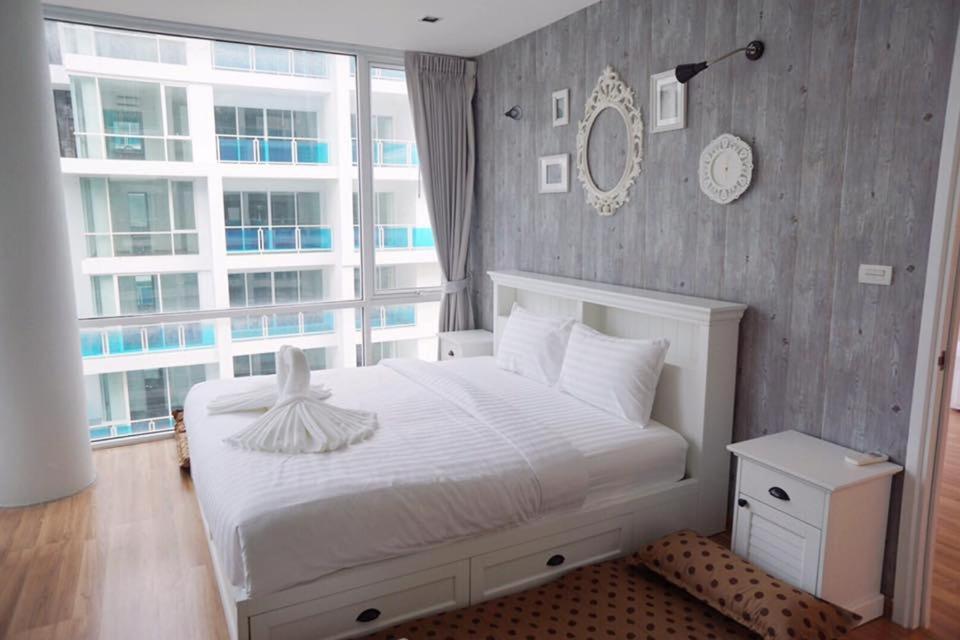 une chambre avec un lit blanc et une grande fenêtre dans l'établissement My Resort Hua Hin A502, à Hua Hin