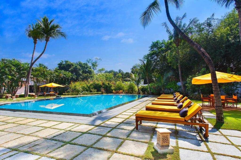 a swimming pool with lounge chairs and umbrellas at Trident Chennai in Chennai