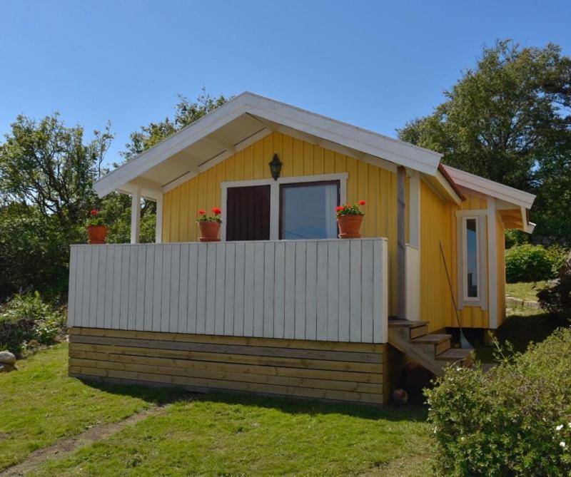una pequeña casa amarilla con una valla blanca en Stuga 3 en Hamburgsund