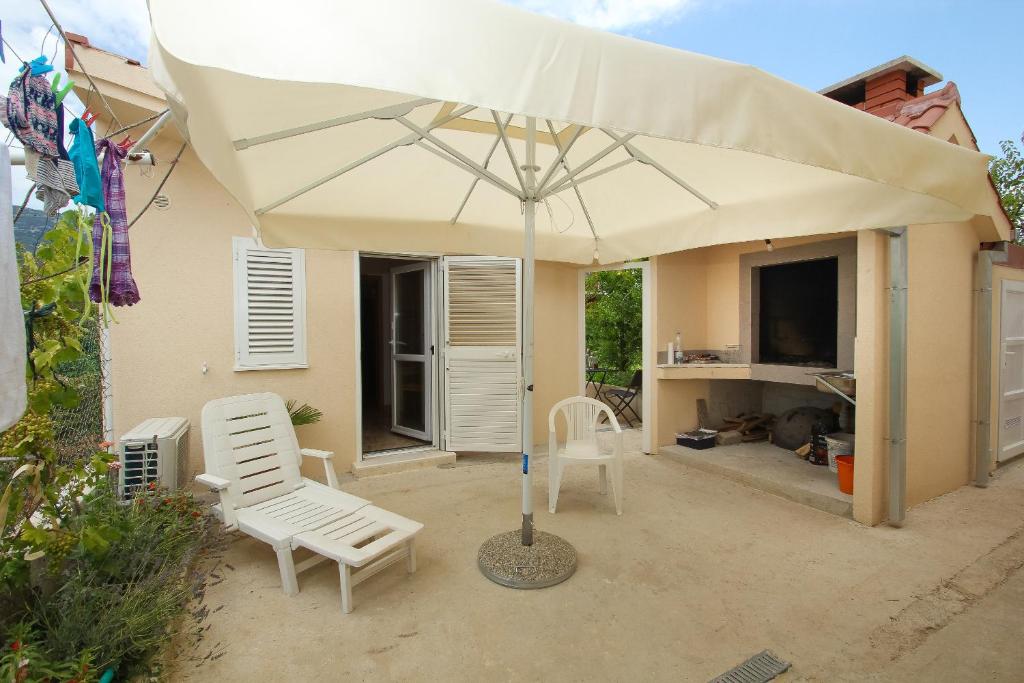 un grande ombrellone bianco su un patio con due sedie di Apartment Hello Kitty a Kaštela (Castelli)