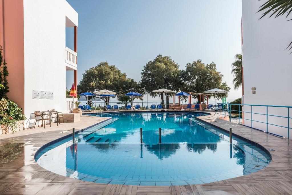 a pool at a resort with chairs and umbrellas at Eden Beach Hotel in Agia Marina Nea Kydonias