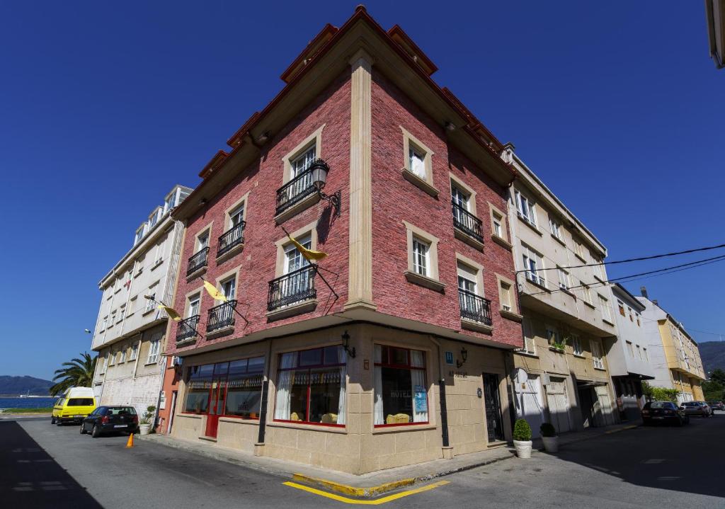 un grand bâtiment en briques rouges dans une rue dans l'établissement As Areas I, à Viveiro