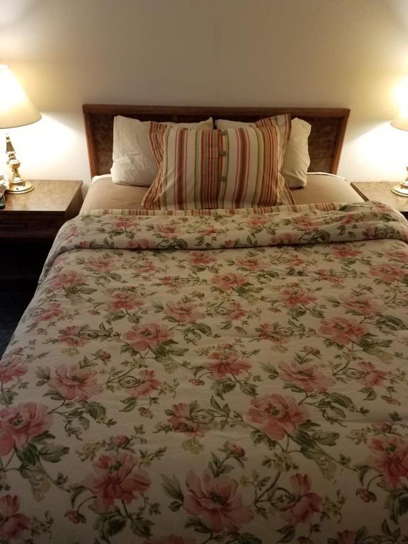 a bedroom with a bed with a floral bedspread at Sleep For Less Motel in Sidney