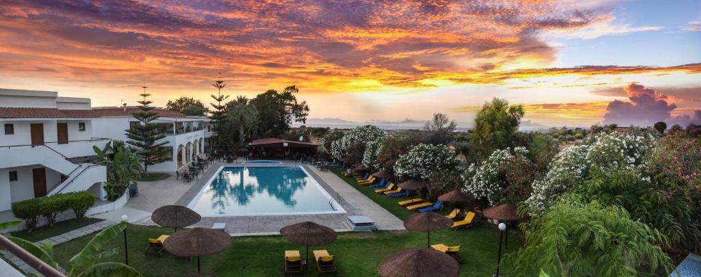uma vista aérea de um resort com uma piscina e um pôr-do-sol em Vallian Village Hotel em Paradeísion