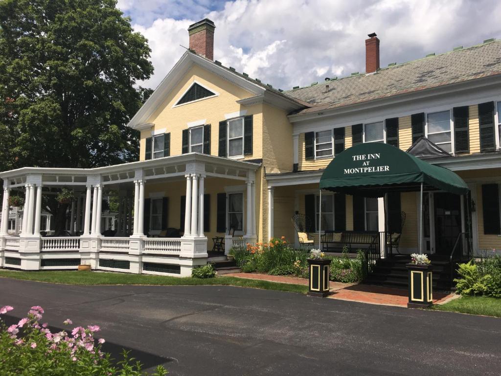 een wit huis met een groene luifel op een straat bij The Inn at Montpelier in Montpelier