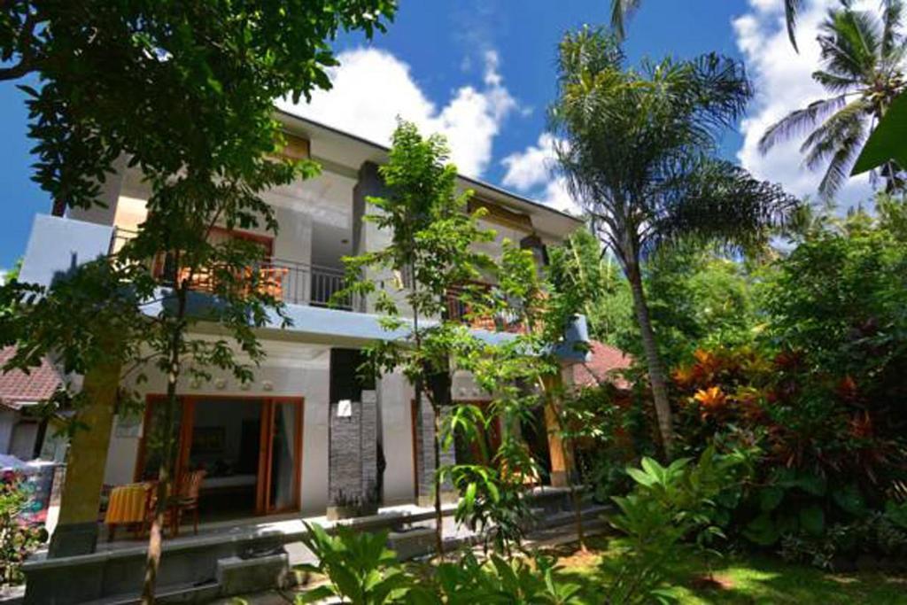 a white house with trees in front of it at Artja Inn Ubud in Ubud