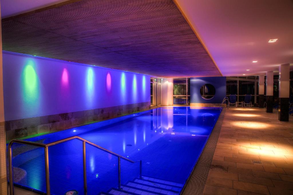 a swimming pool in a building with blue lights at Hotel Grossfeld in Bad Bentheim