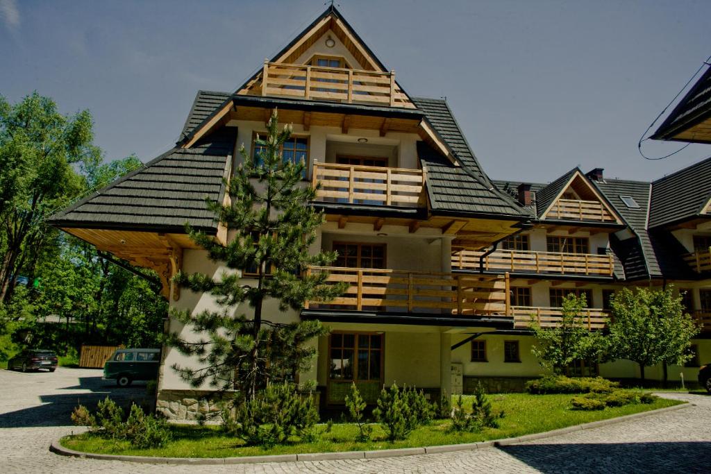 a large wooden house with a gambrel roof at Bellamonte Aparthotel in Zakopane
