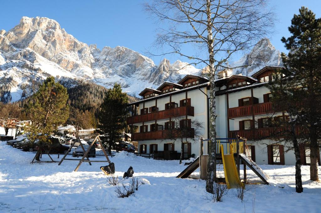 a snow covered ski slope with a building at Relais Clubresidence in San Martino di Castrozza