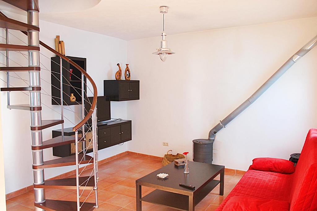 sala de estar con sofá rojo y escalera en Casa Rural Fuente Caraila, en Júzcar