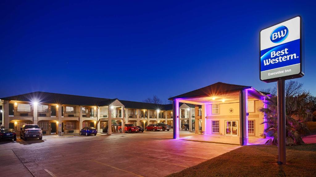 a best western sign in front of a building at Best Western Executive Inn in Hallettsville