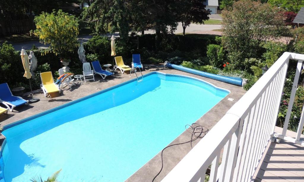 a large blue swimming pool with chairs and a fence at Ranger's Retreat Bed & Breakfast in Niagara on the Lake