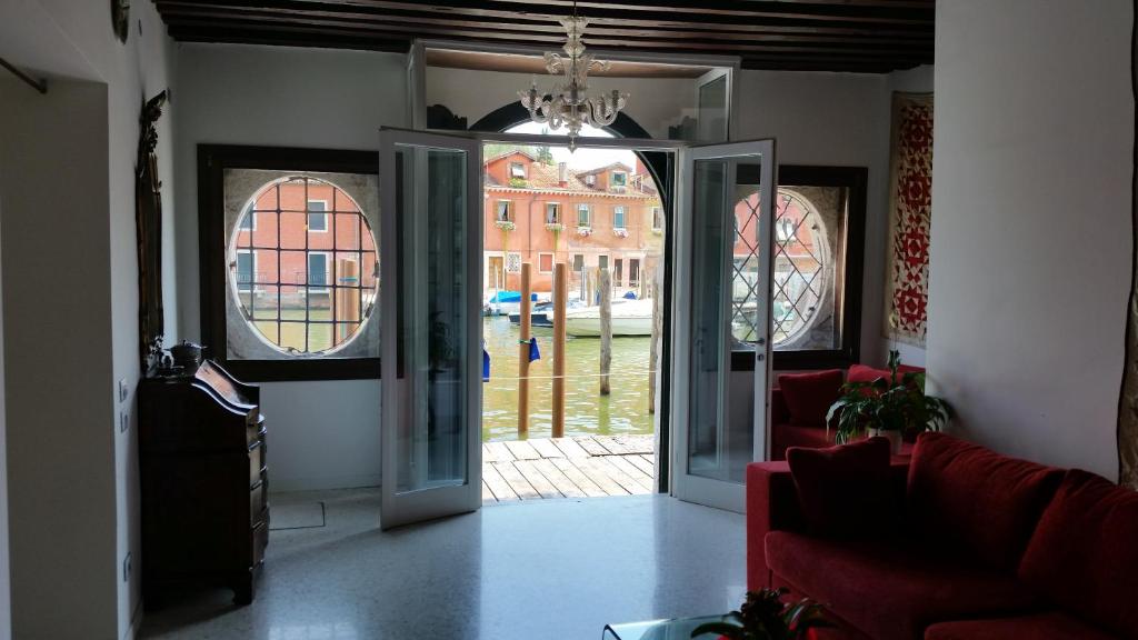 a living room with an open door with a red couch at Elisabeth Waterfront Apartment in Venice