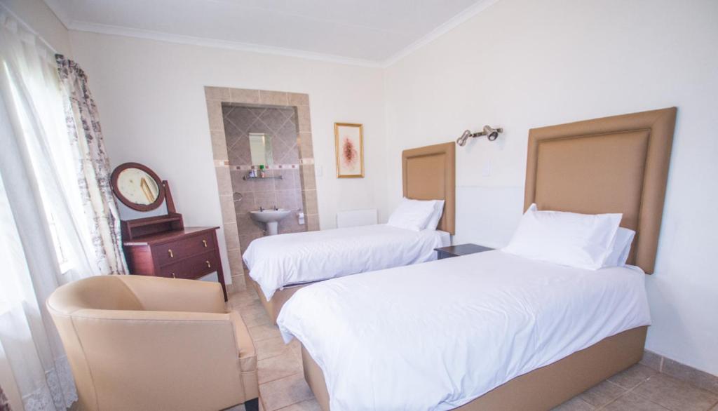 una habitación de hotel con 2 camas y una silla en Hoyohoyo Machadostud Lodge, en Helvetia Noord
