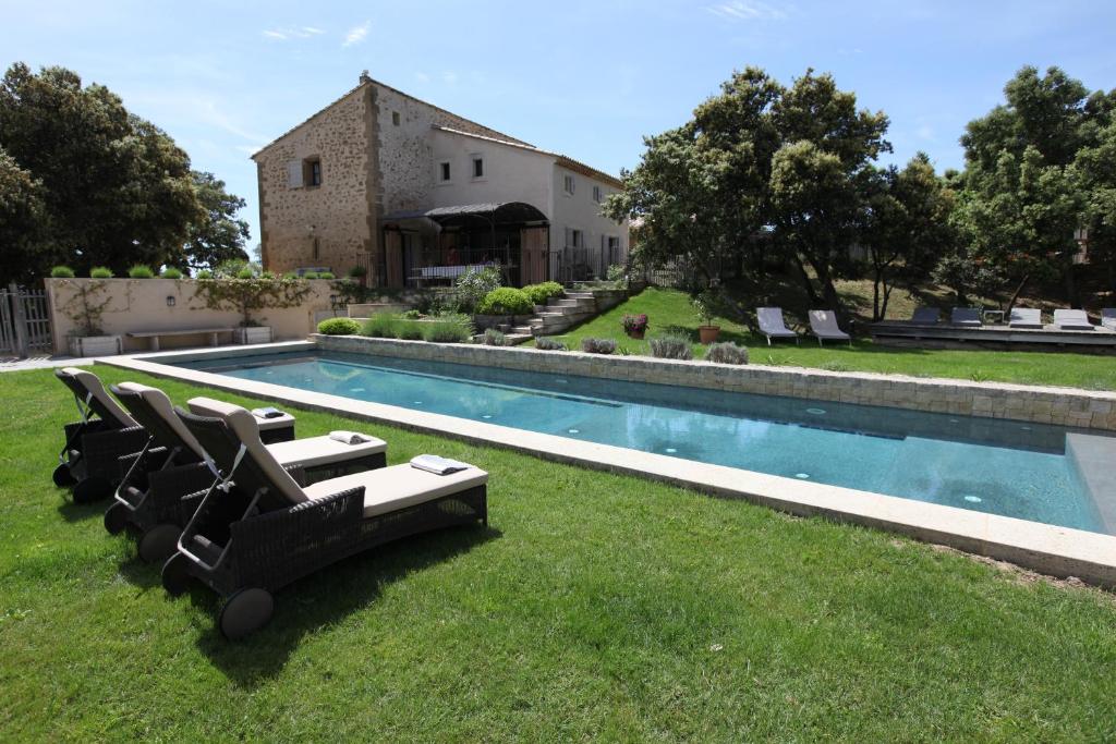 a group of chairs sitting on the grass next to a pool at La bergerie de Nano in Beaumes-de-Venise