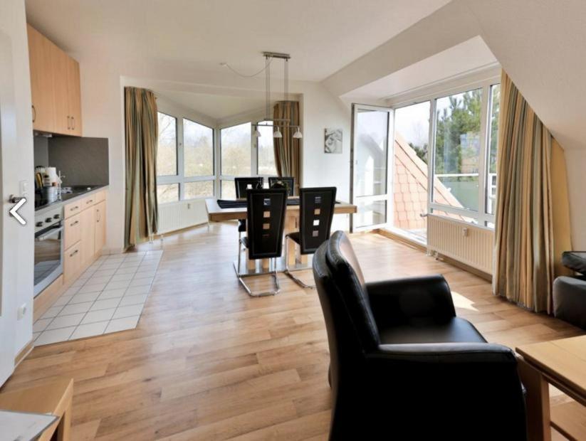 ein Wohnzimmer mit einem Tisch und Stühlen sowie eine Küche in der Unterkunft Appartement 34 - Ostseedomizil in Timmendorfer Strand