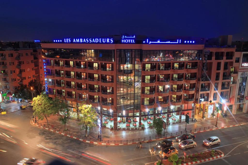 Appart Hotel Les Ambassadeurs في مراكش: مبنى كبير على شارع المدينة ليلا