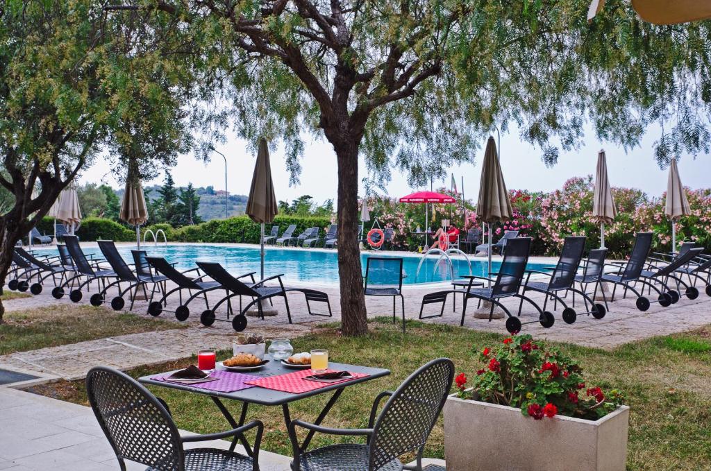 einen Tisch und Stühle neben einem Pool in der Unterkunft Castellaro Golf Resort in Castellaro