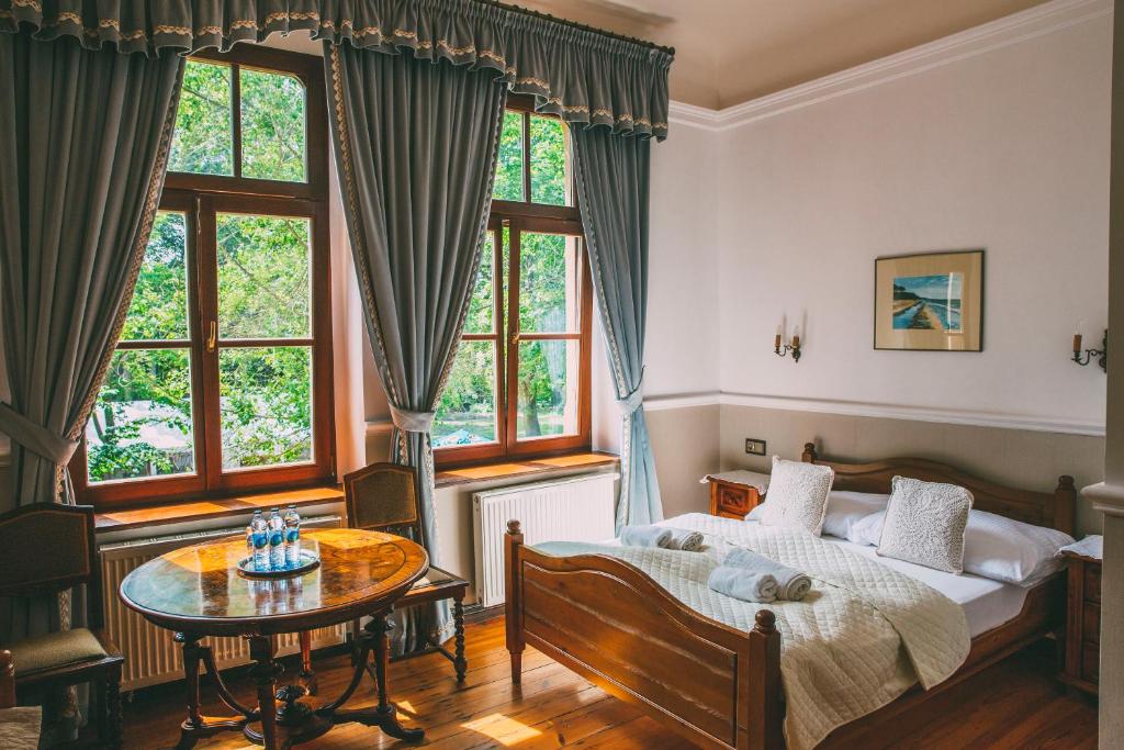 a bedroom with a bed and a table and windows at Pałac Poraj in Wicko