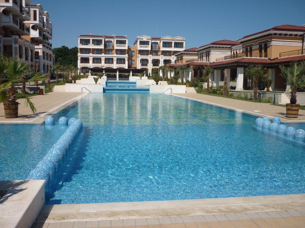 a large blue swimming pool with buildings in the background at Ganozliev's Apartments in Kavatsi Area in Sozopol