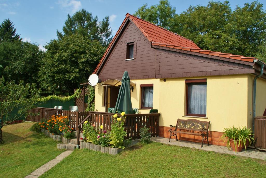 una casa amarilla con una valla, un banco y flores en Ferienhaus Schaffrath en Ehrenberg