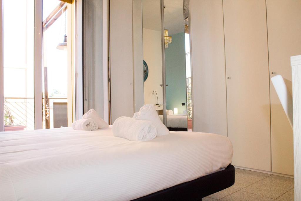 una camera da letto con letto, lenzuola e cuscini bianchi di GetTheKey Vicolo Bianco Apartment a Bologna