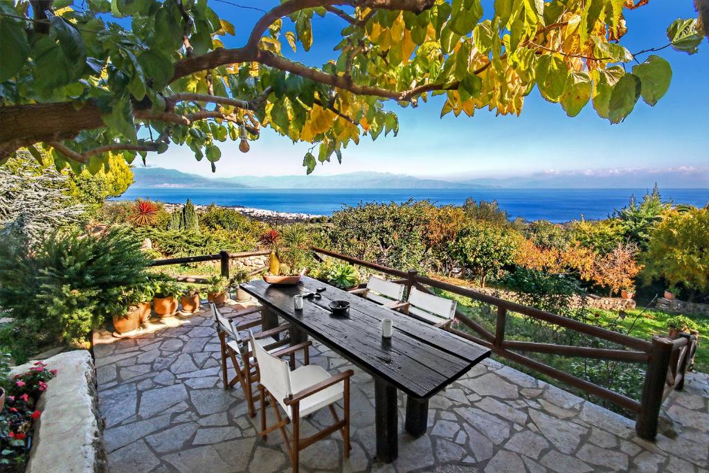 uma mesa e cadeiras num pátio com vista para o oceano em Ampelos Estate em Akrata