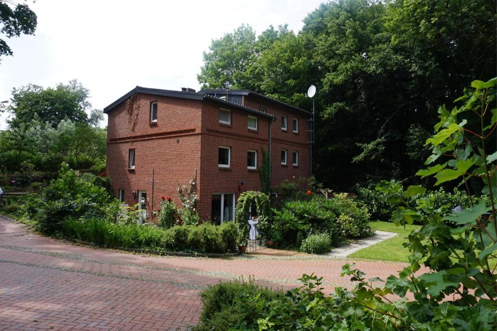 ein rotes Backsteingebäude mit einem Garten davor in der Unterkunft Ferienwohnung am Mühlenpark in Timmendorfer Strand