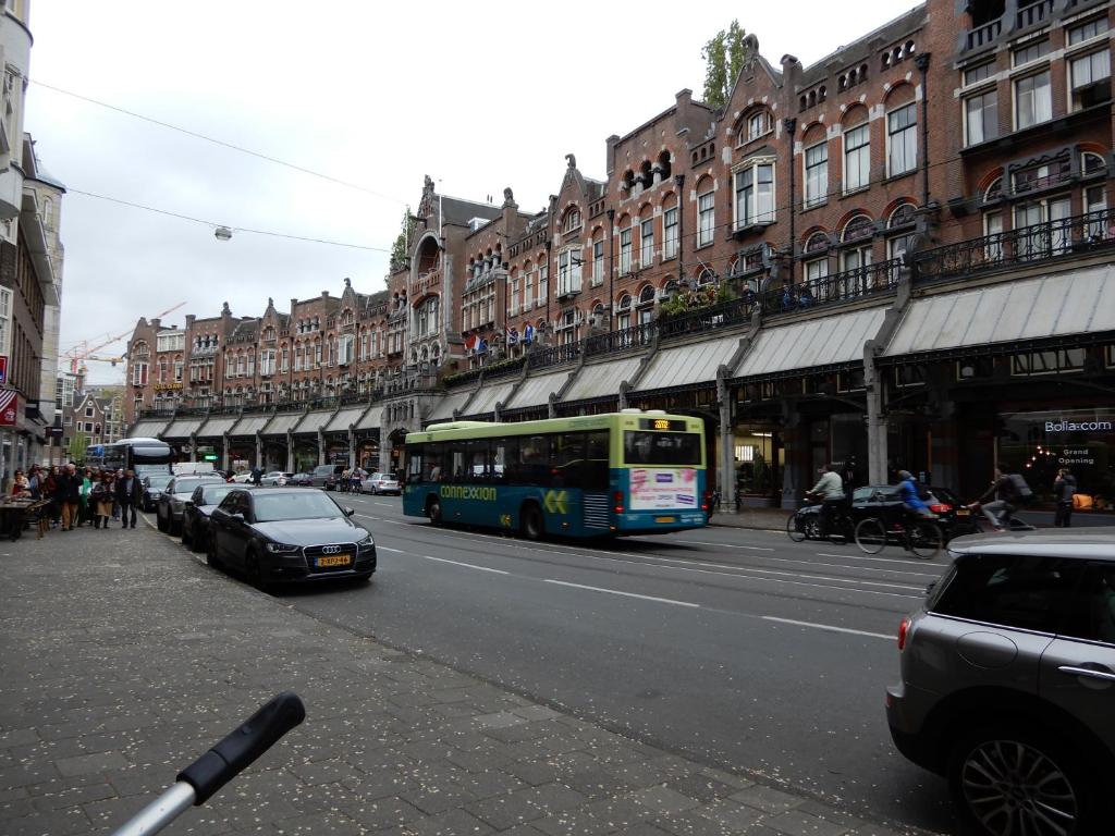 a bus driving down a city street with buildings at Hotel Sharm in Amsterdam