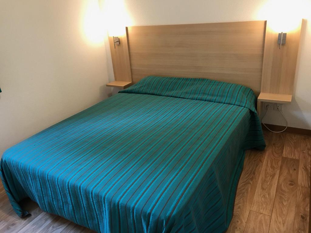 sypialnia z łóżkiem z niebieską narzutą w obiekcie Appartement T3 Luchon w mieście Luchon