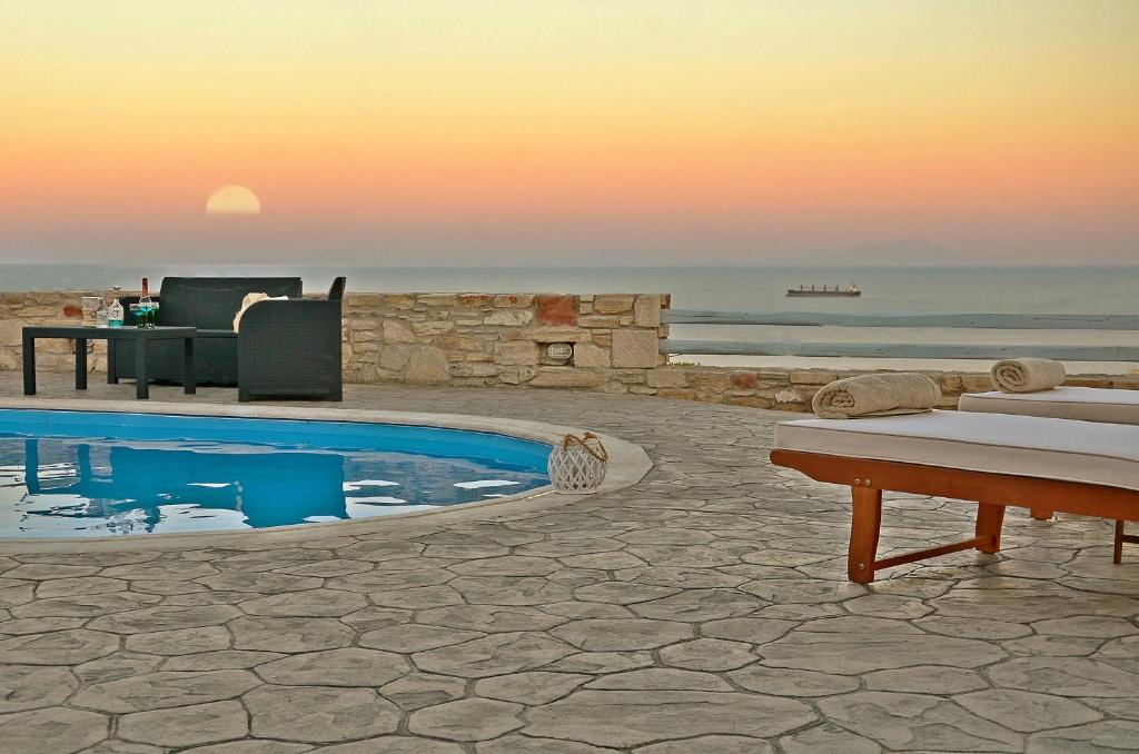 a pool with a view of the ocean at sunset at Mastiha Villas in Chios
