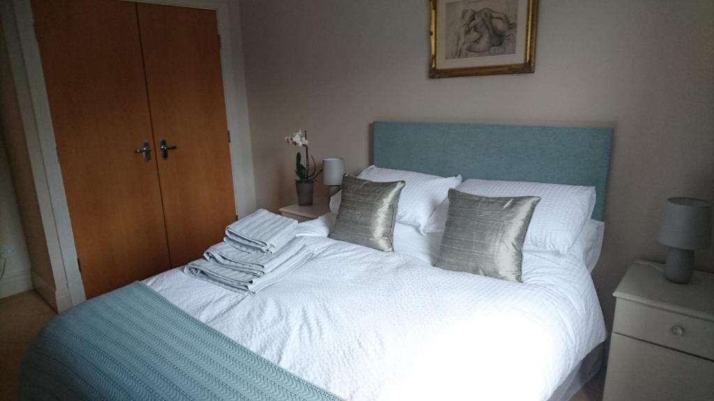 Schlafzimmer mit einem Bett mit weißer Bettwäsche und Kissen in der Unterkunft 12 Emperors Wharf in York