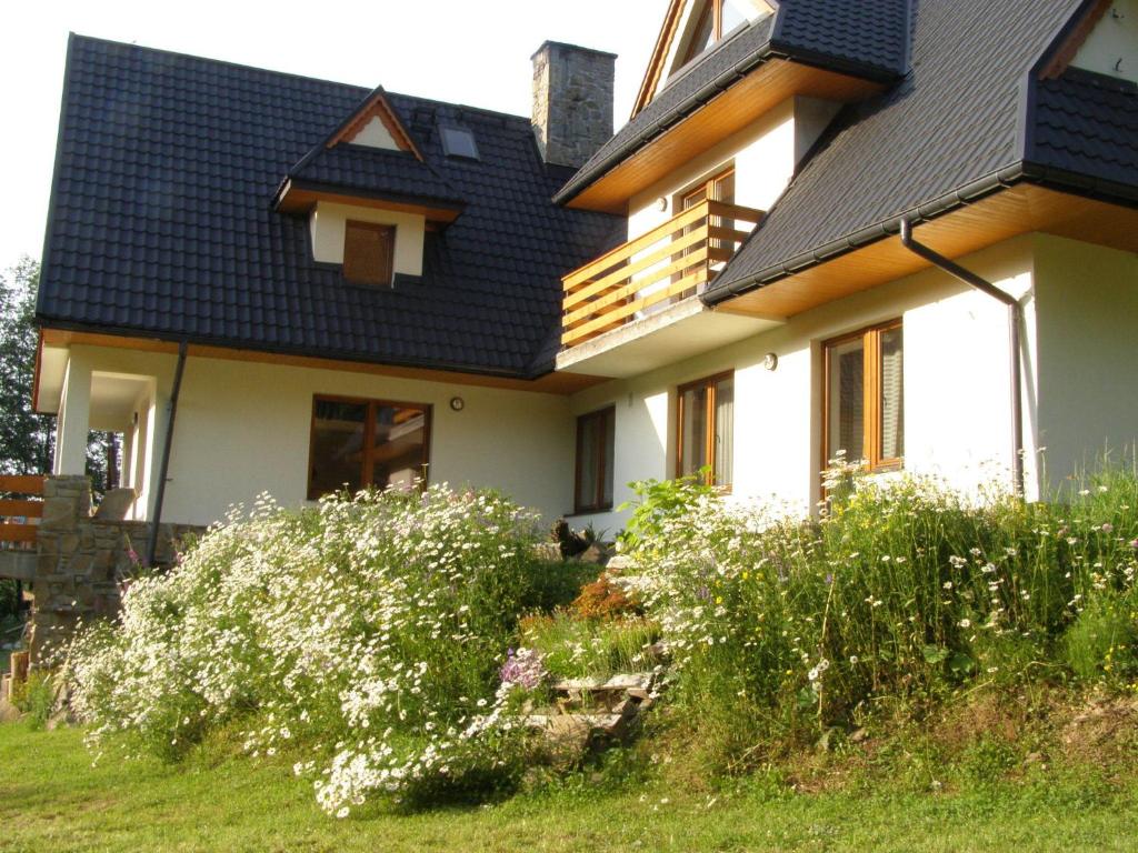 a house with a black roof and some flowers at Dom Gościnny Na Skolach in Gliczarów