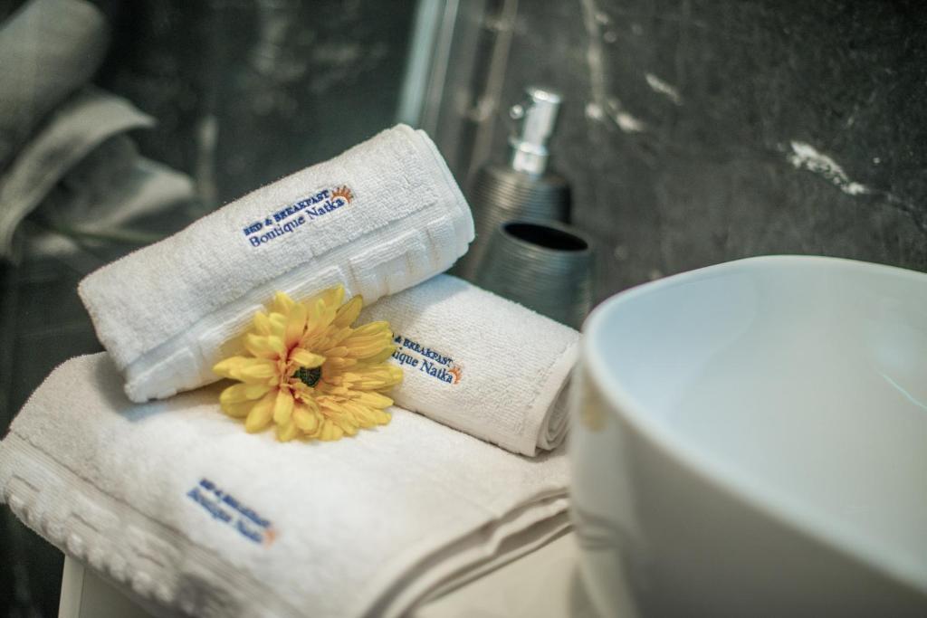 łazienka z ręcznikami i kwiatem na górze toalety w obiekcie Hotel Boutique Natka w Rovinj