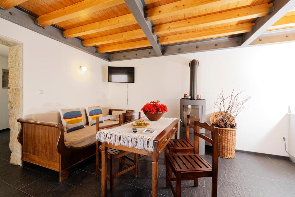 a living room with wooden ceilings and a table and chairs at Antiga "Casa do Porco" in Viseu