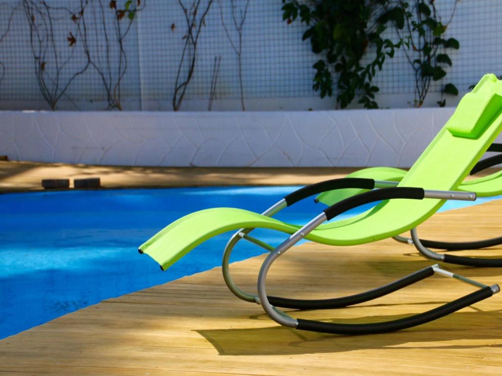 a green chair sitting next to a swimming pool at La Tonnelle Guest House in Trou aux Biches