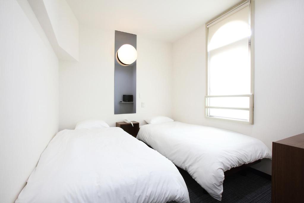 倉敷市にある倉敷グローバルホテルの窓のある白い部屋にベッドが2つある
