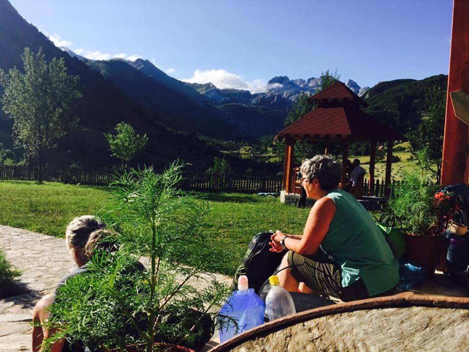 een groep mensen op een bankje in een tuin bij Guesthouse Alpini in Lëpushë