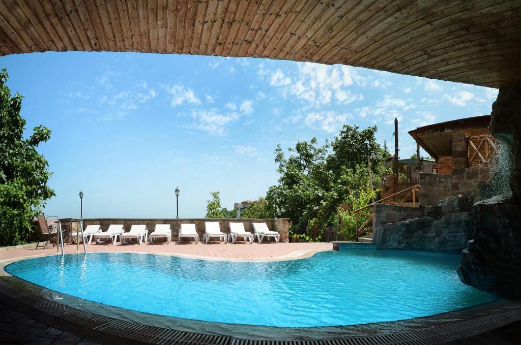 a large swimming pool with chairs and a blue sky at Hotel Brigitte in Sighnaghi