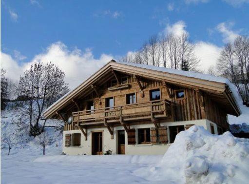 una cabaña de madera con nieve delante en Chez La Fine, en Les Gets