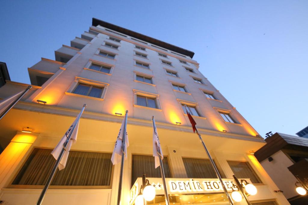 a tall white building with flags in front of it at Demir Hotel in Diyarbakır