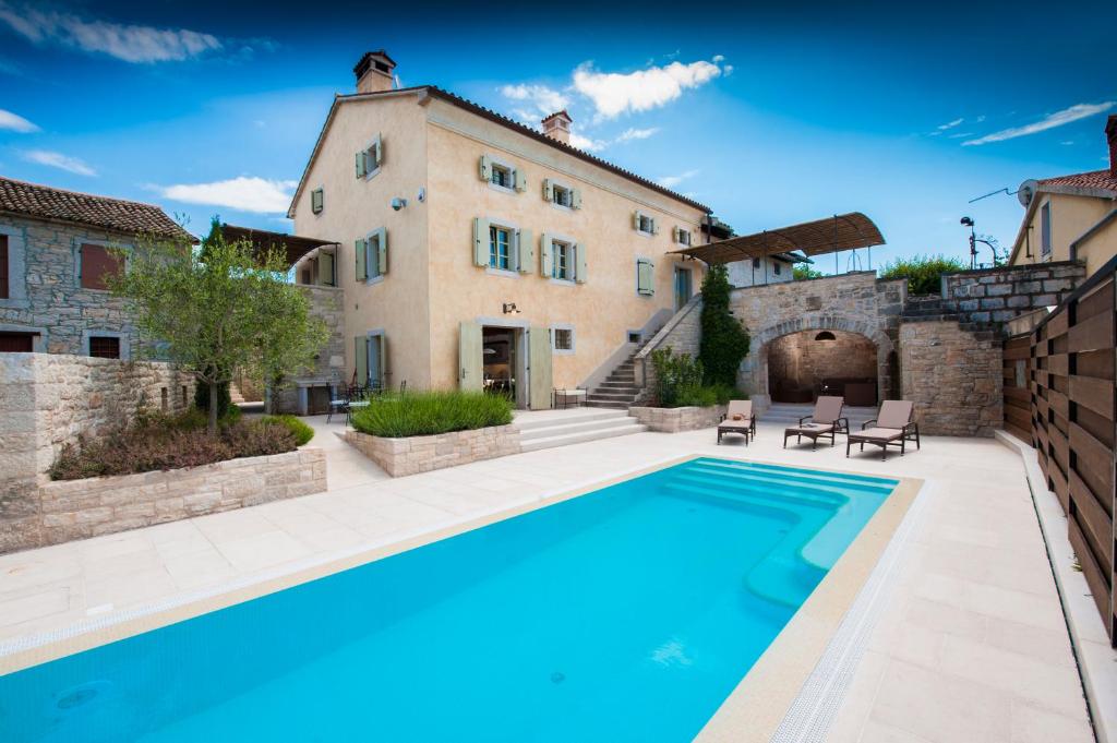 a house with a swimming pool in front of a building at Villa Tona in Višnjan