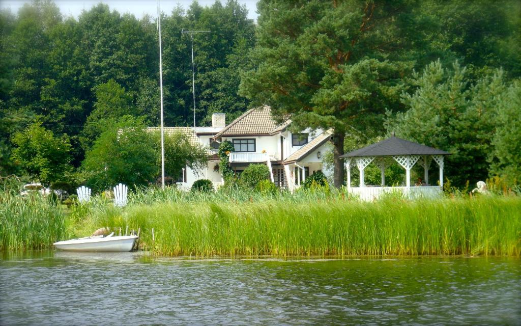 a small boat in front of a house on the water at Käsmu Merekalda Apartments - Adults only in Käsmu