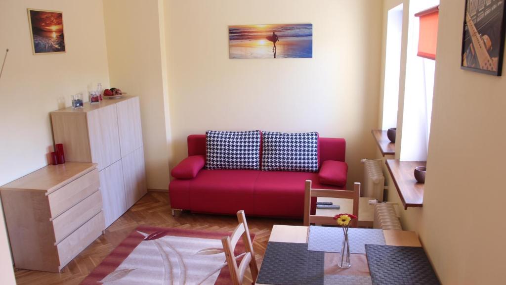 グディニャにあるApartament Słonecznyのリビングルーム(赤いソファ、テーブル付)
