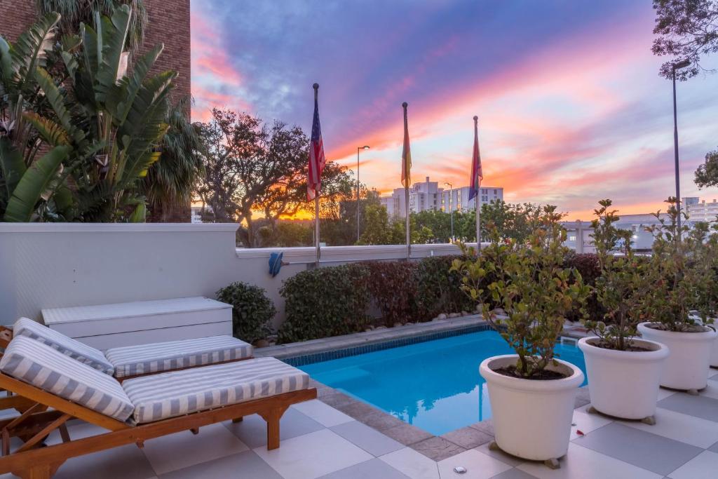 a patio with a swimming pool with flags and plants at Head South Lodge in Cape Town