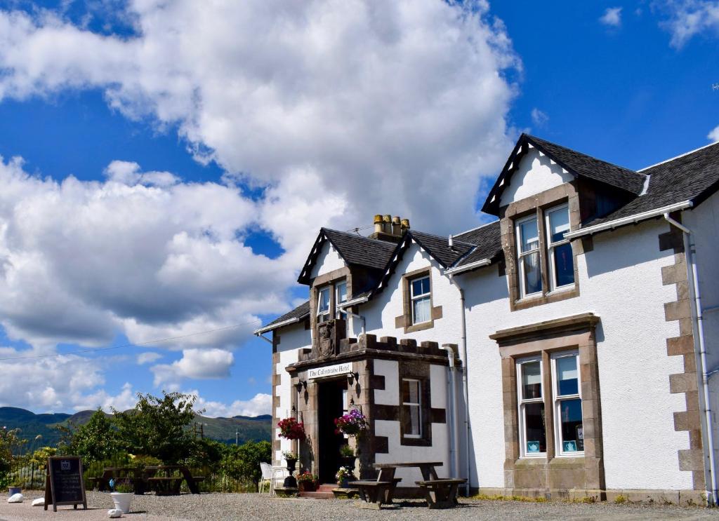 a white house with a blue sky and clouds at The Colintraive in Colintraive