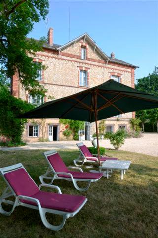 deux chaises longues et un parasol devant une maison dans l'établissement Le Bois de Rome, à Conches-en-Ouche