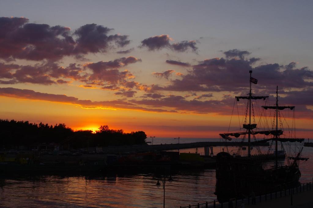 a boat in the water with the sunset in the background at Syrenka Apartamenty in Ustka